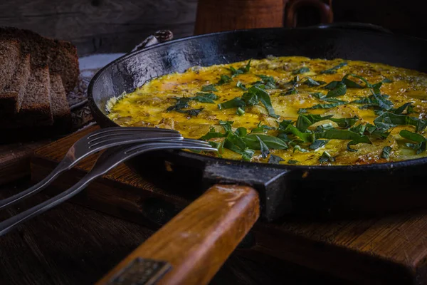 Rustic omelet with potatoes in a cast-iron pan cooked in the oven.