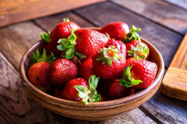 Çilekler eski ahşap bir masada, toprak eşyalar içinde. Mutfakta yemek pişirmek..