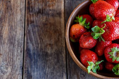 Çilekler eski ahşap bir masada, toprak eşyalar içinde. Mutfakta yemek pişirmek..