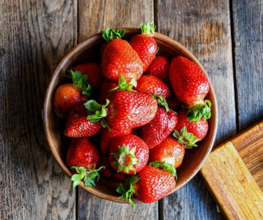 Çilekler eski ahşap bir masada, toprak eşyalar içinde. Mutfakta yemek pişirmek..