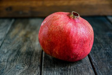 Olgun kırmızı nar meyvesi eski bir ahşap masada yatıyor..