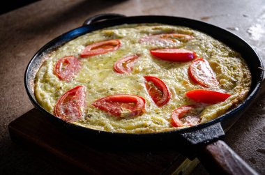 Dökme demir tavada patates ve domatesli Rustik omlet..