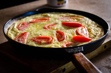 Dökme demir tavada patates ve domatesli Rustik omlet..