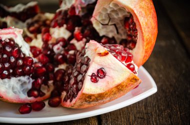 Mutfakta beyaz bir tabakta dilimlenmiş, pişirilmiş nar. Mutfakta yemek pişirmek..