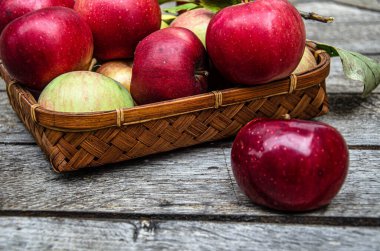 Elmaları hasat et, hasır bir sepetin içinde, ahşap bir masada..