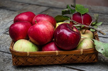 Elmaları hasat et, hasır bir sepetin içinde, ahşap bir masada..
