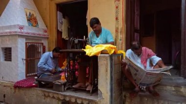 Varanasi, Hindistan - Kasım 2019. Adam Varanasi 'nin dar sokaklarındaki atölyesinde dikiş makinesine kıyafet dikiyor..