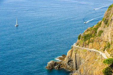 İtalya, Riomaggiore yakınlarındaki kayalık dağlık kıyı ve mavi denizin güzel manzarası.