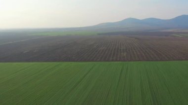 Bir çift tepenin altındaki geniş ve geniş bir arazide kameralı bir drone ile uçmak yağmurlu bir günde manzaralı bir arka plan yaratır.