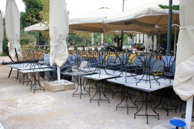 Yunanistan, Atina, 3 Kasım 2020 - Covid-19 tecrit duyurusu sonrasında Akropolis tepesi yakınlarındaki kapalı kafe restoranının önünde yığılmış sandalyeler, masalar ve diğer mobilyalar.