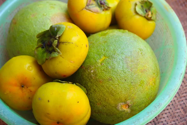 Kaki und Grapefruit im Korb — Stockfoto