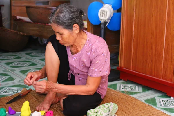 Mujer vieja exprimir juguetes para niños con polvo de arroz de color — Foto de Stock