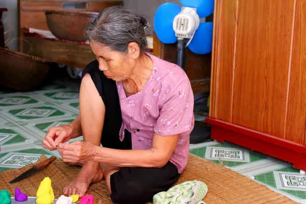 Mujer vieja exprimir juguetes para niños con polvo de arroz de color — Foto de Stock