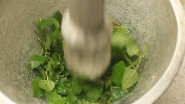 Close up pounding fresh herbs in a mortar with a pestle. — Stock Video
