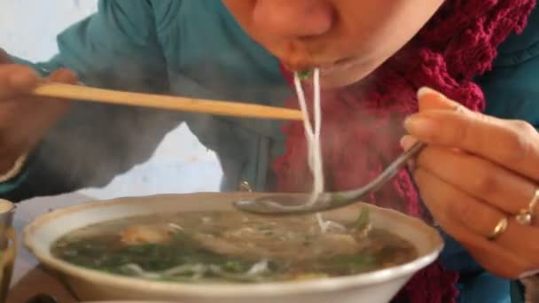 Vrouw eet traditionele noodle in straat eetgelegenheden — Stockvideo