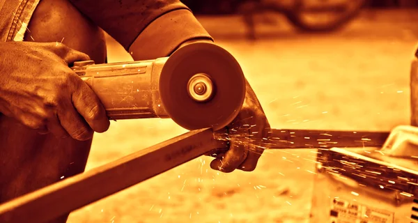 Trabalhador usando um pequeno moedor para cortar metal — Fotografia de Stock