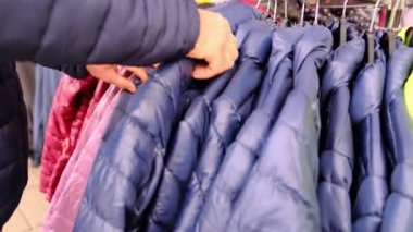 Sokaktaki kıyafetler, alışveriş yapan erkekler, mağazadaki askılarda aynı kıyafetleri giyerler, moda, alışveriş, mevsimlik satışlar, tüketici malları için yüksek fiyatlar.