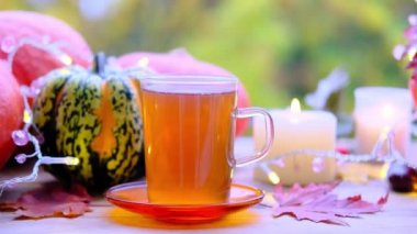 Çay fincanındaki çay fincanının kaplaması tabağın üzerindeki ahşap masa yeşil arka plan, balkabakları yalan, mumlar yanıyor, sabah konsepti, mevsimlik sonbahar havası, sağlıklı yaşam tarzı