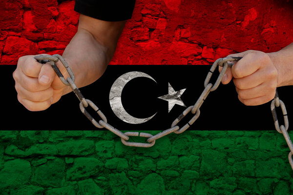 male hands break the iron chain, symbol of tyranny, protest against the background of the national flag of Libya, the concept of political repression, arrest, crime, civil rights, freedom