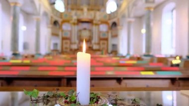 Kilisede bir beyaz mum yanar, parlak bir tapınakta ışıkların bulanıklaşması, Hristiyan dini kavramı, ölen insanların anısına.