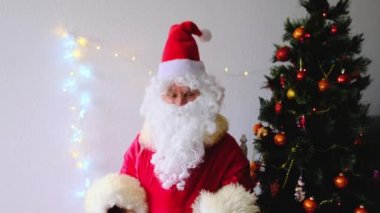 Beyaz sakallı yaşlı Noel Baba çocukları ve yetişkinleri kutluyor, elinde banknotlar tutuyor, onlara para veriyor, Noel konseptine odaklanıyor, tatil indirimleri, alışveriş, hediyeler.