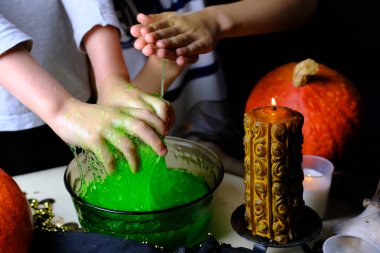 Çocuklar yeşil büyü iksiriyle oynuyor, masa siyah bir bezle kaplı, balkabakları yalan söylüyor, hayvan kafatasları yanıyor, mumlar yanıyor, Cadılar Bayramı konsepti, aşk büyüsü, çocuk partisi