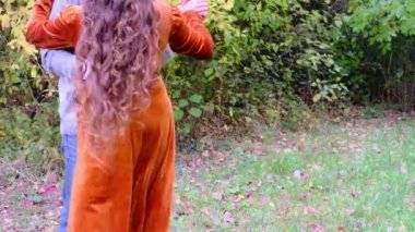 Uzun kıvırcık saçlı güzel bir kadın sonbaharda babasıyla parkta dans ediyor. Sağlıklı yaşam tarzı, iyi ruh hali, aile yürüyüşleri.