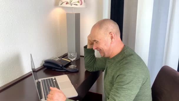 中年男性ノートパソコンのキーボードでテキストを入力します アパートでインターネットサーフィン ホテルの部屋 ビジネス旅行の概念 リモートワーク — ストック動画