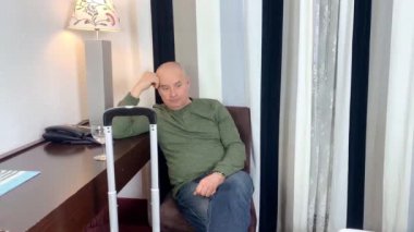 Orta yaşlı bir adam bir apartman dairesinde, otel odasında bir sandalyeye oturur, içki içer, kafa yorar, iş seyahati, turizm, hayattaki zorluklar...