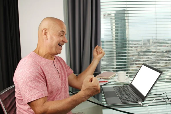 Adam bir dizüstü bilgisayarın arkasında çalışıyor. Modern Avrupa şehrinin penceresinin önündeki bir ofiste boş ekranla. İş fikirleri konsepti, işyeri.