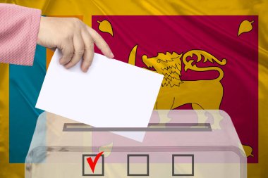 Kadın seçmen, Sri Lanka 'nın ulusal bayrağı, devlet seçimleri konsepti ve referandumun arka planına karşı saydam bir sandıkta oy kullanıyor.