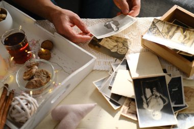 an elderly man looks through his old photographs of 1960-1965, the concept of nostalgia and memories of youth, childhood, remembering his life, relatives, family connection of generations clipart