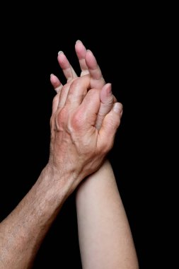 Erkek ve kadın elleri siyah arkaplanda, kırışıklıkları ve damarları olan yaşlı cilt, sağlık konsepti, yaşla ilgili değişiklikler, aşk, aşık bir çiftin hassas ilişkisi, izole bir imaj.