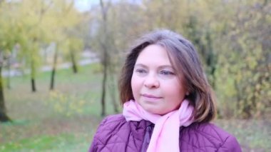 Ceket giymiş orta yaşlı bir kadın parkta yürüyor, açık hava yürüyüşü konsepti.