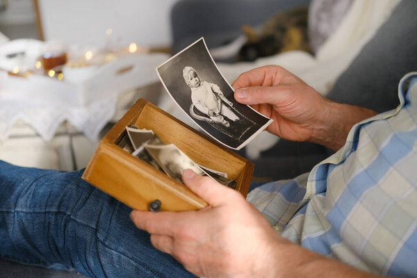 пожилой человек просматривает свои старые фотографии 1960-1965 годов, концепцию ностальгии и воспоминания о юности, детстве, вспоминая свою жизнь, родственников, семейную связь поколений