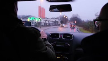 Araba yağmurda şehir boyunca gider, sokak lambalarının bulanık ışıkları, pencere su damlaları, trafik konsepti ile yırtılır.