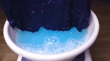 Kadınlar ellerini yıkıyor. Mavi erkek külotlarını leğende örüyor, temiz çamaşır konsepti yapıyor. Kirli çamaşırları yıkıyor.