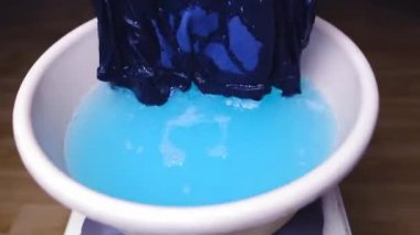 Kadınlar ellerini yıkıyor. Mavi erkek külotlarını leğende örüyor, temiz çamaşır konsepti yapıyor. Kirli çamaşırları yıkıyor.