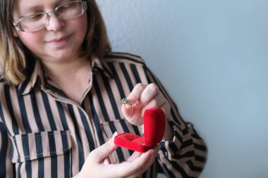 Yetişkin bir kadın içinde mücevher olan kırmızı kutuyu tutar, açar, tatil konsepti, evli çiftin yıldönümü, sevgililer günü, doğum günü, sevgililer günü, sevgililer günü, anne, mutlu noeller