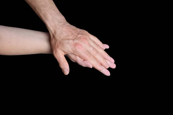 male and female hands together on black background, old skin with wrinkles and veins, concept of health, age-related changes, love, tender relationship of a couple in love, isolated image