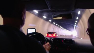 İsviçre dağlarında uzun, lamba ışıklı bir tünelde araba sürücüsü seçici bir şekilde araç gösterge paneline, otomobil seyahat konseptine, pozitif çıkışa, yol trafiğine odaklanıyor.