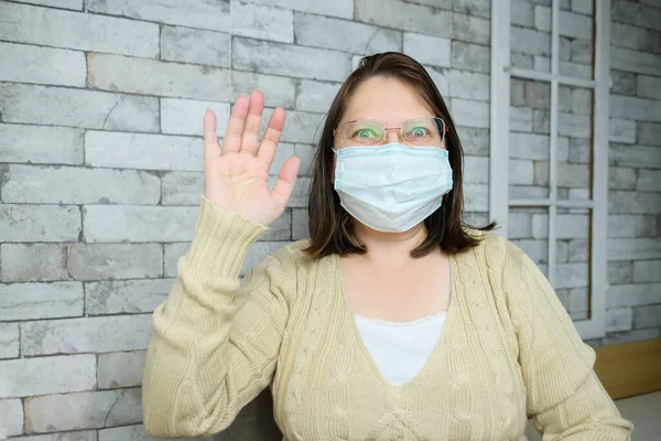 안경과 의료용 마스크를 착용하고 중년의 여성은 집에서 비디오 손으로 제스쳐 — 스톡 사진