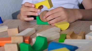 Çocuk, çocuk renkli ahşap figürlerden kuleler ve binalar inşa ediyor, konut inşaatı konsepti, mortgage, sigorta, mutlu çocukluk, çocuk oyunları
