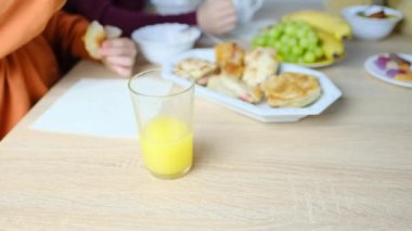 6-7 yaş arası çocuk bir tabak makarnadan yemek yer ve portakal suyuyla içer. İştah kavramı, bebek maması.