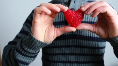 Ceketli genç adam elinde kırmızı bir kalp mankeni, aşkın sembolü, günah çıkarma konsepti, Sevgililer Günü, aşk ilanı, evlilik teklifi.