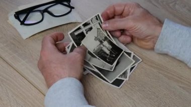 Erkek elleri 1950 'lerin eski fotoğraflarına dokunuyor, ahşap masa üzerindeki eski fotoğraflar, soy ağacı konsepti, aile ağacı, atalarımızın hafızası.