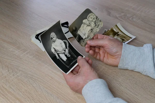 Stare Męskie Dłonie Trzymają Retro Rodzinne Zdjęcia Nad Albumem Monochromatycznymi — Zdjęcie stockowe