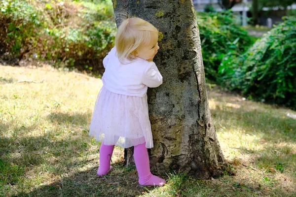 Little Kid Girl Blonde Hair Stands Tree Park Hides His — Stock Photo, Image