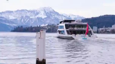 Yolcu gemisi Lucerne Gölü 'nde yelken açar, İsviçre' nin kırmızı bayrağı dalgalanır, martılar suyun üzerinde dalgalanır, karla kaplı dağlar uzaktan görülebilir, turizm, seyahat, ekoloji, ulaşım konsepti