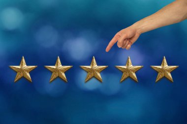 Erkek müşterinin elinde mavi arka planda beş altın folyo yıldızı var. Sonuçları değerlendirme konsepti, değerlendirme, memnuniyet.